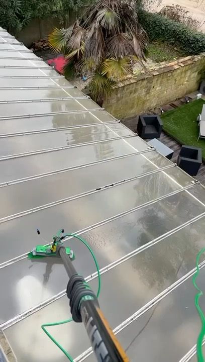 Perche télescopique en train de nettoyer les vitres d'une véranda