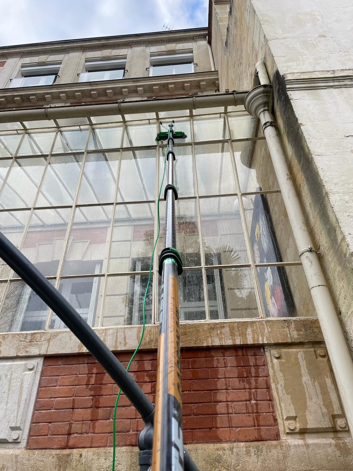 Perche télescopique en train de nettoyer les vitres d'une verrière