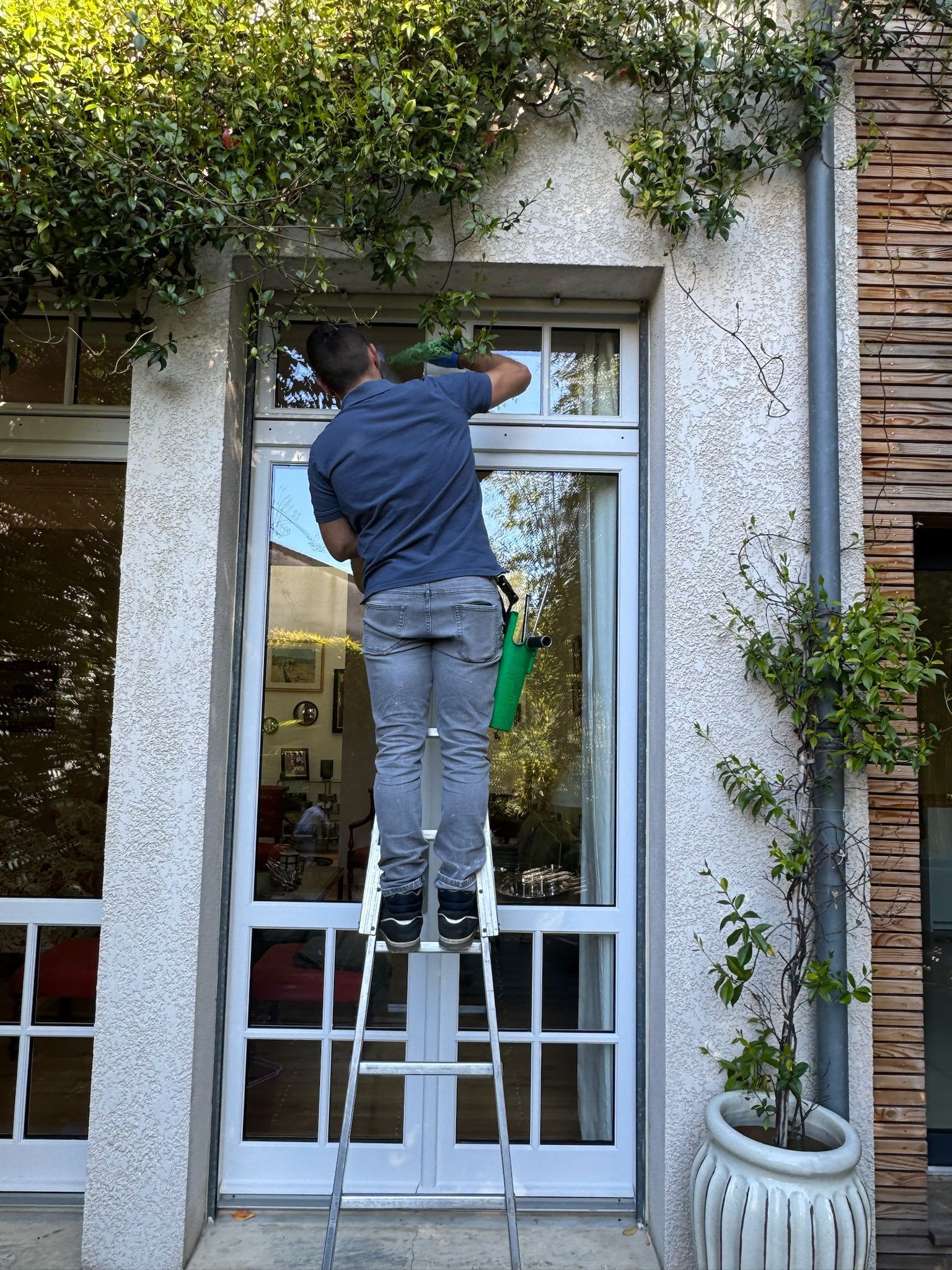 Agent d'entretien sur une échelle pour un nettoyage de vitres en hauteur
