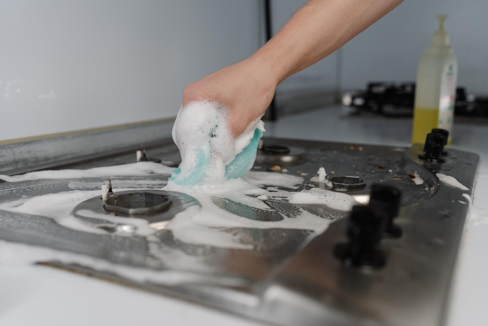 Limpiar a mano una superficie de cocina enjabonada con una esponja en una cocina.