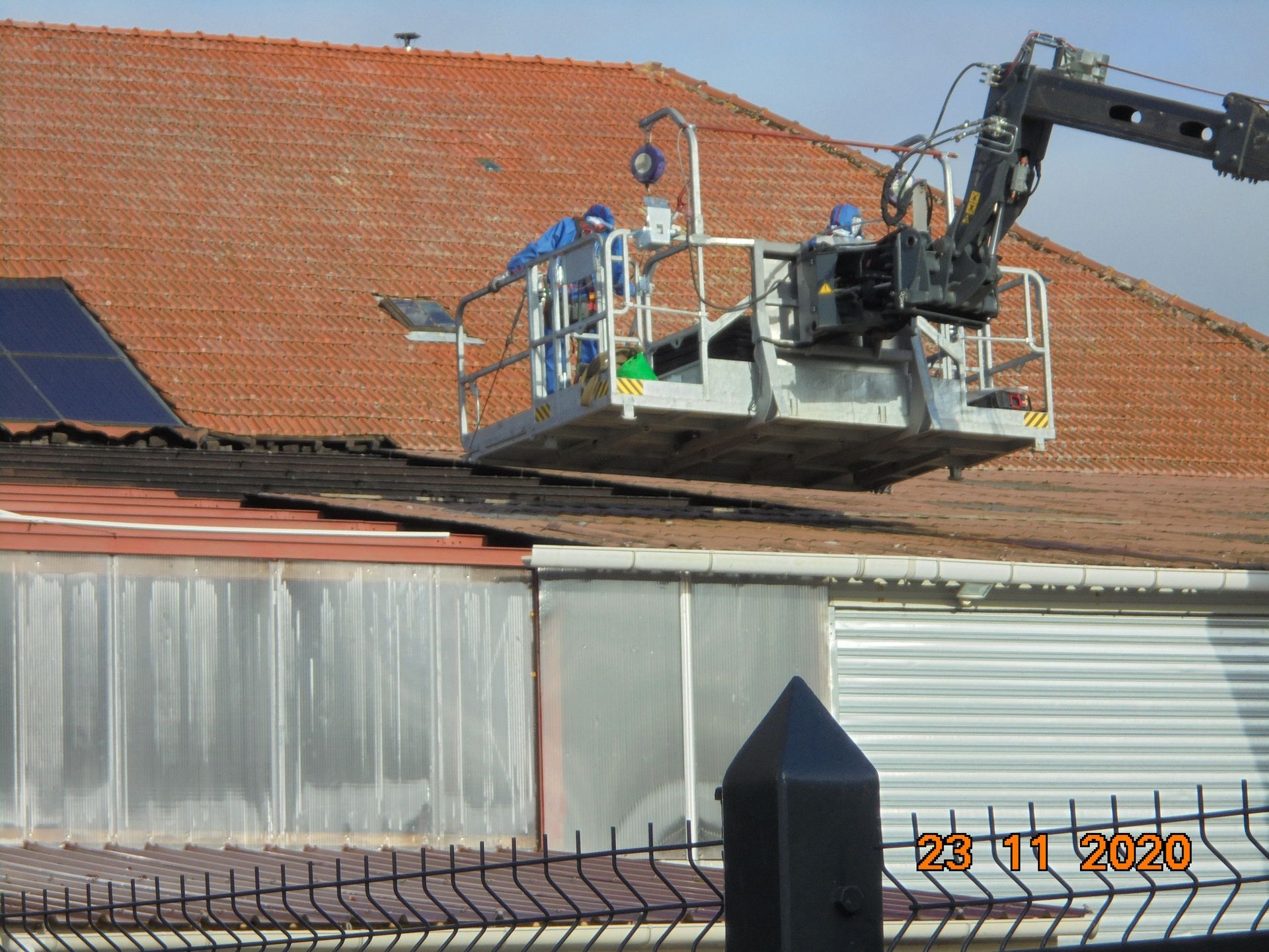 Personne en train d'intervenir sur un toit à l'aide d'une nacelle