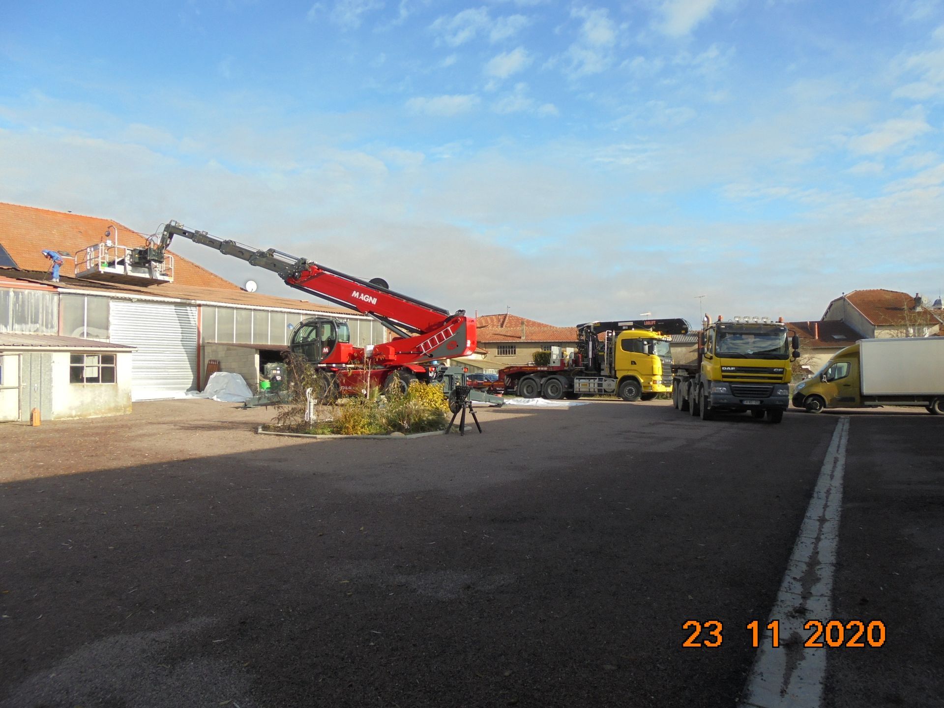 Chariot Magni rouge avec nacelle télescopique et personne en train d'intervenir sur un toit