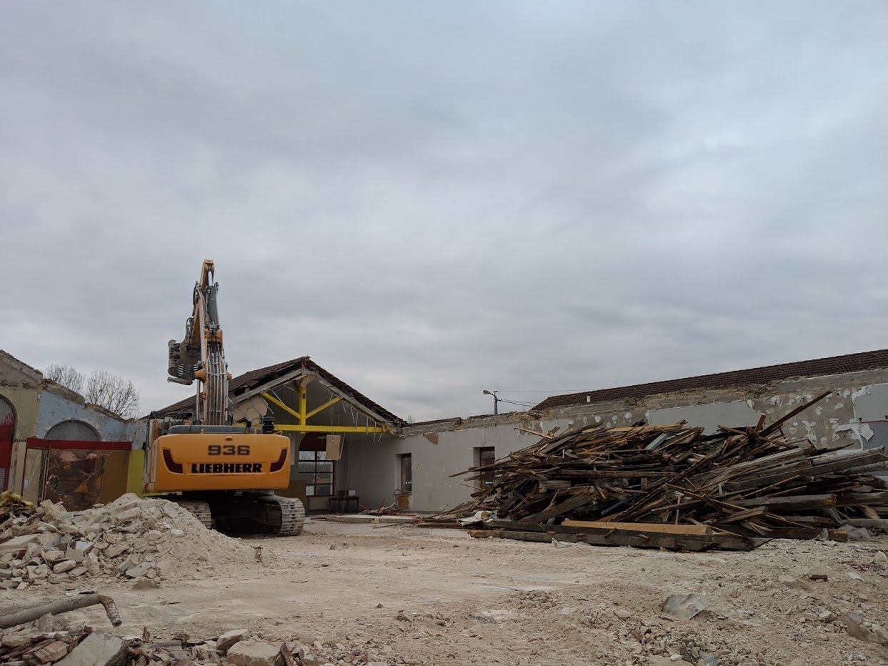 Grosse pelle jaune en train de détruire un ancien entrepôt