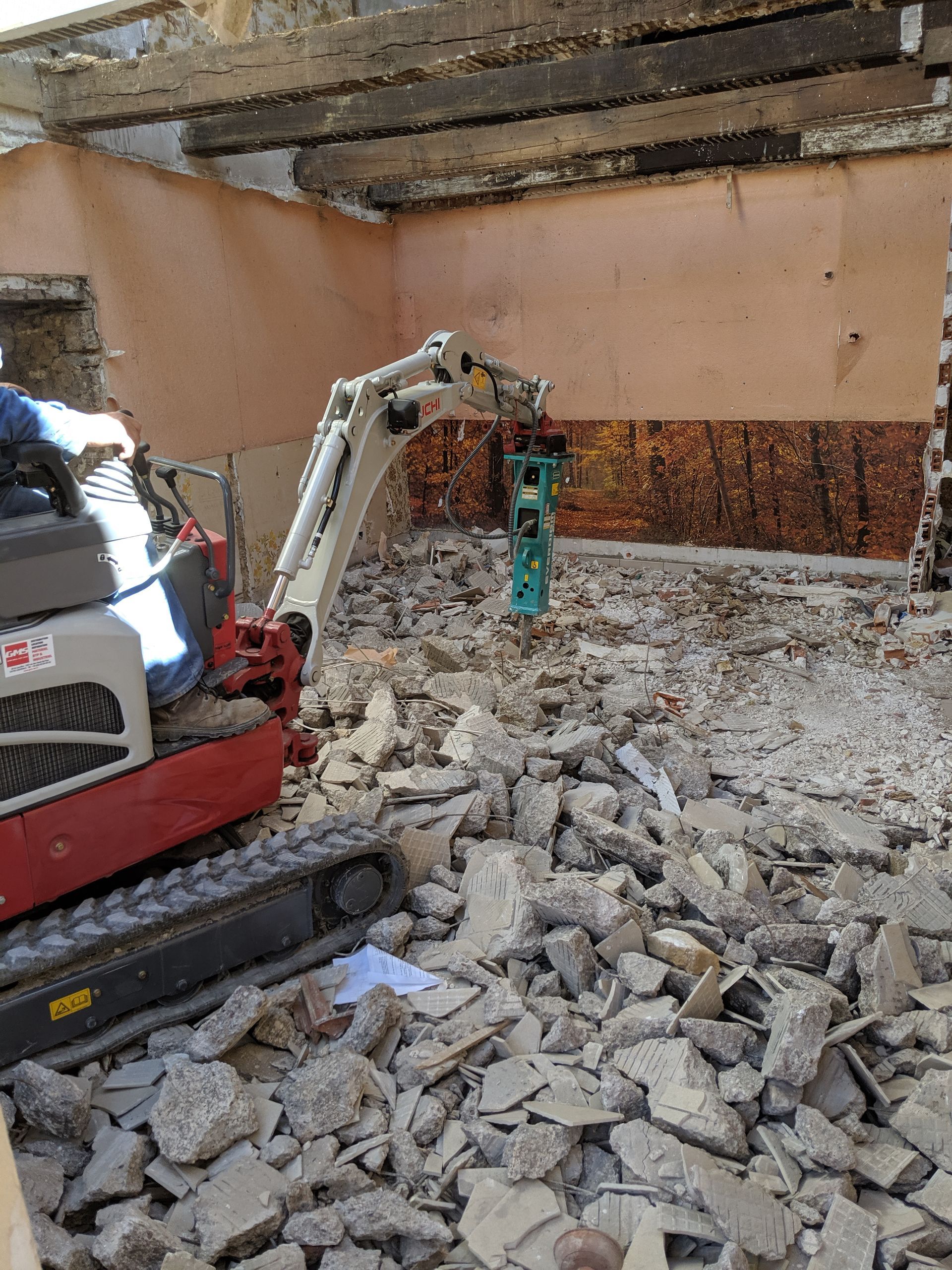 Destruction d'un sol avec une minipelle et un marteau-piqueur hydraulique