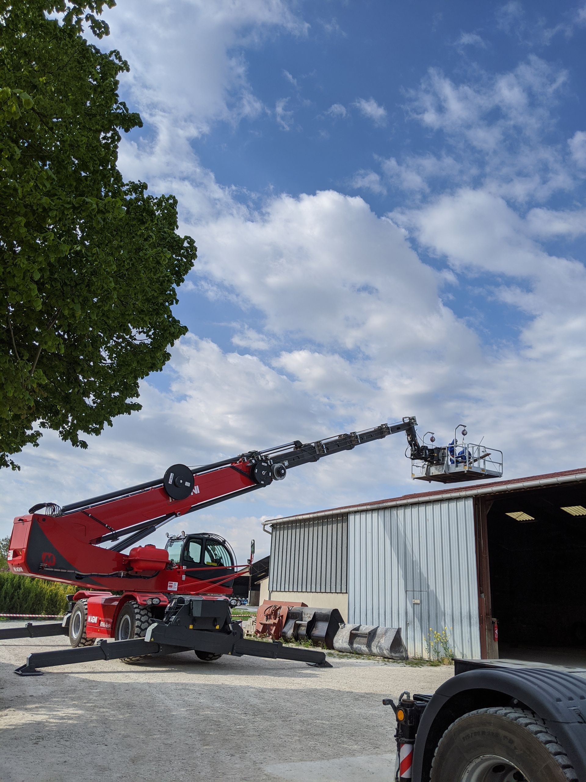 Chariot rouge Magni avec nacelle en train d'être déployé sur le toit d'un ancien entrepôt