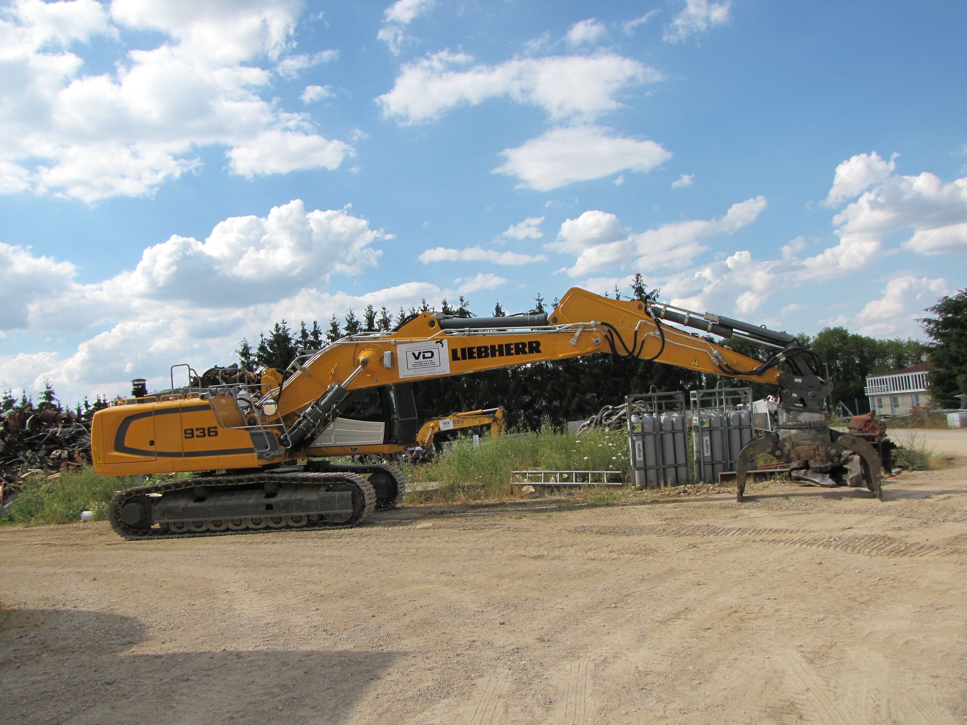 Tractopelle Liebherr jaune avec pince vue de côté à l'arrêt