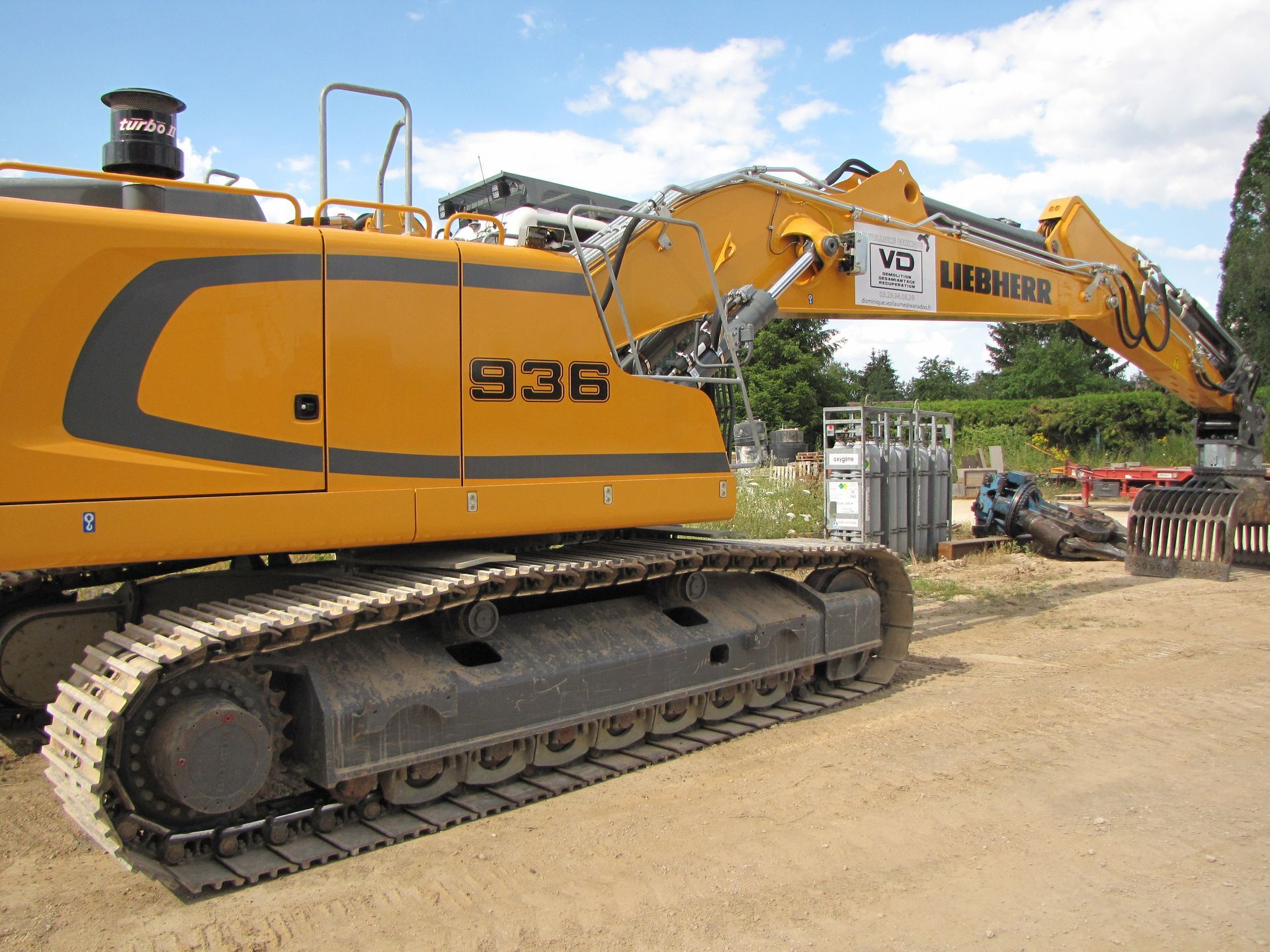 Tractopelle Liebherr jaune avec pince à l'arrêt