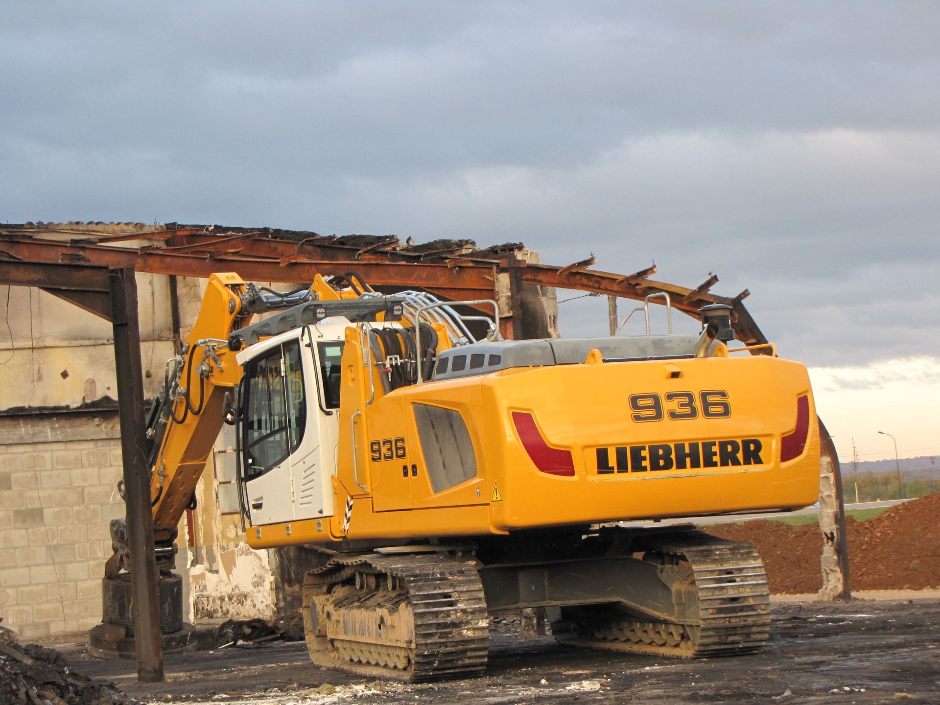 Tractopelle Liebherr jaune avec pince vue de derrière en action