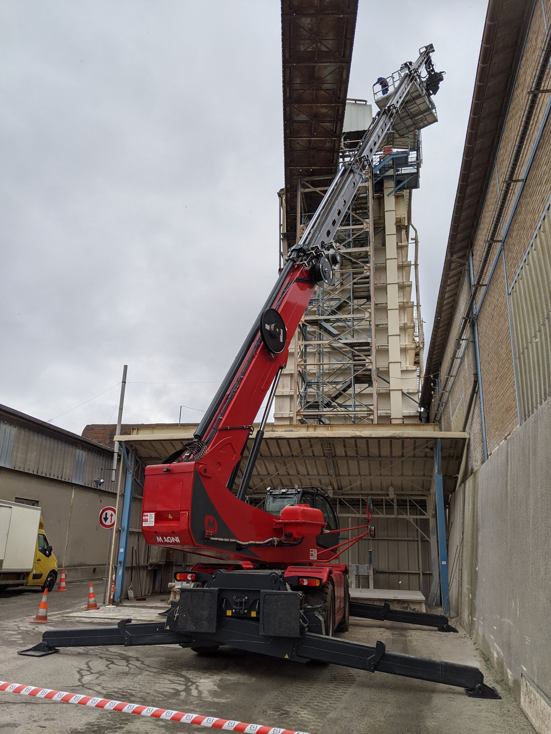 Grue rouge télescopique en intervention sur grand bâtiment d'usine