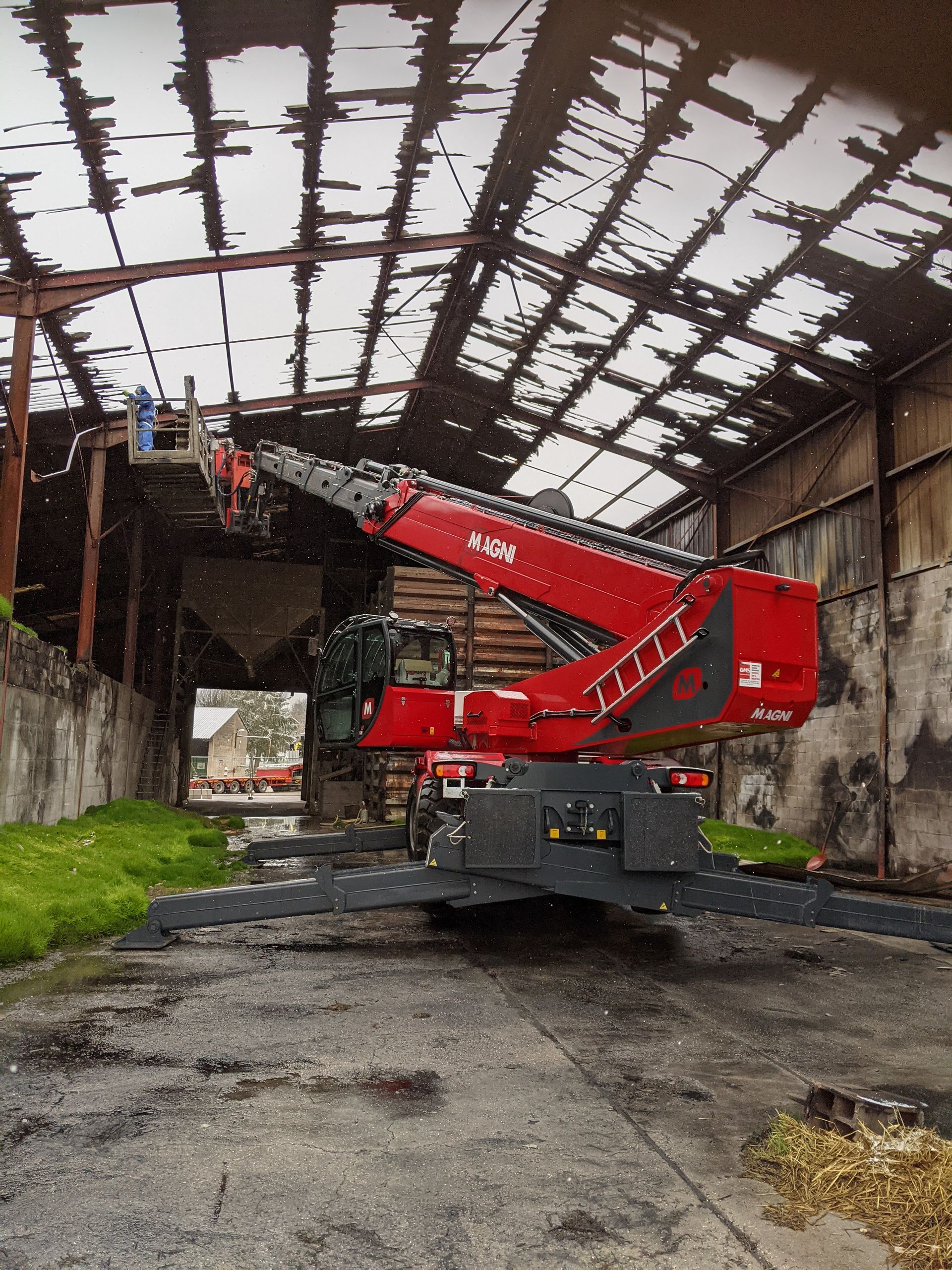 Grue rouge télescopique avec nacelle pour intervention sur la destruction d'un toit d'usine