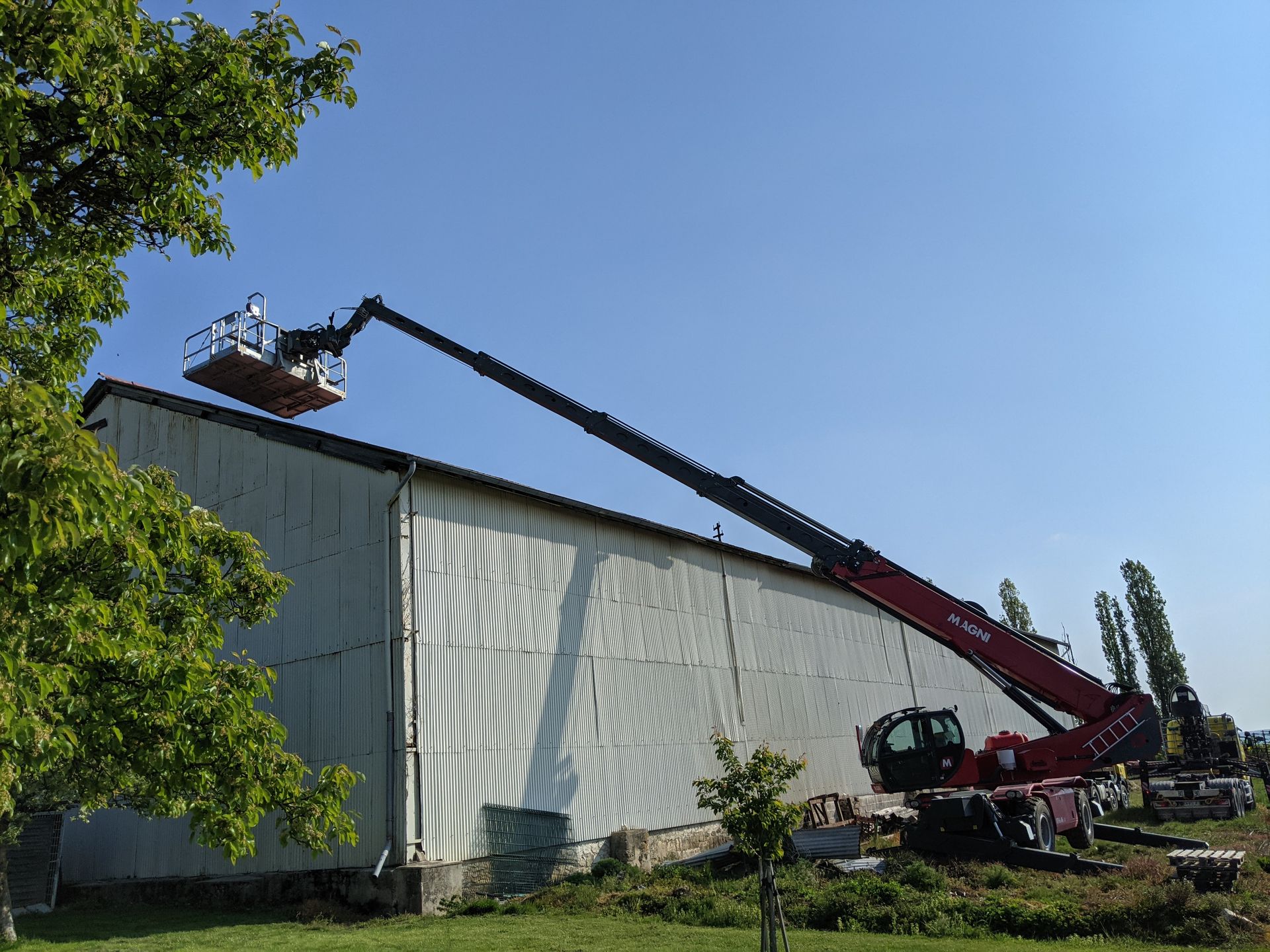 Grue rouge télescopique avec nacelle vers bâtiment d'entrepôt