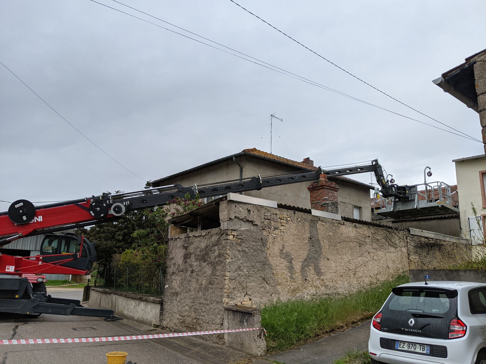 Grue rouge télescopique avec nacelle pour intervention sur maison