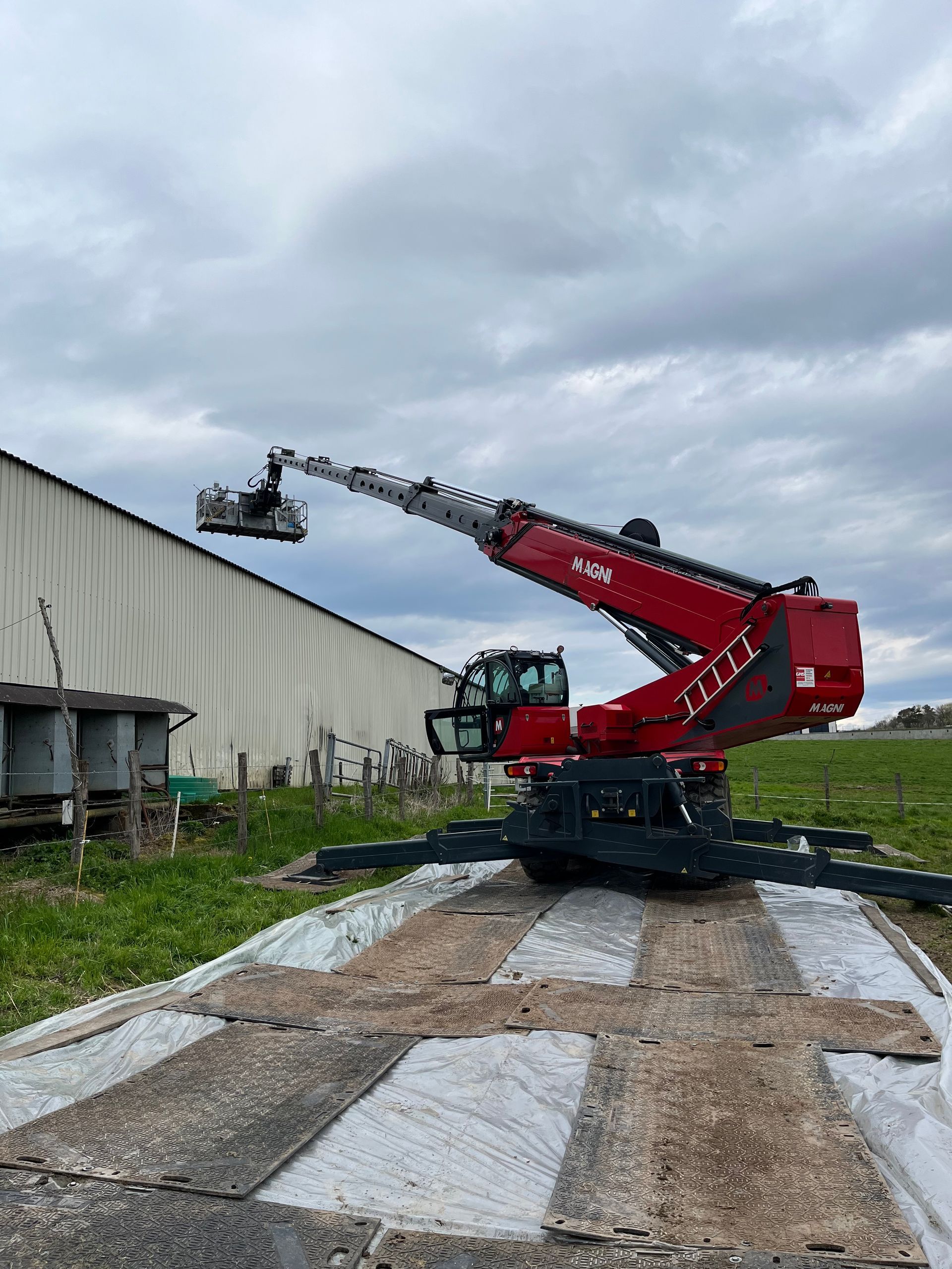 Chariot rouge Magni monté sur stabilisateur araignée avec nacelle déployée sur le bâtiment d'une usine