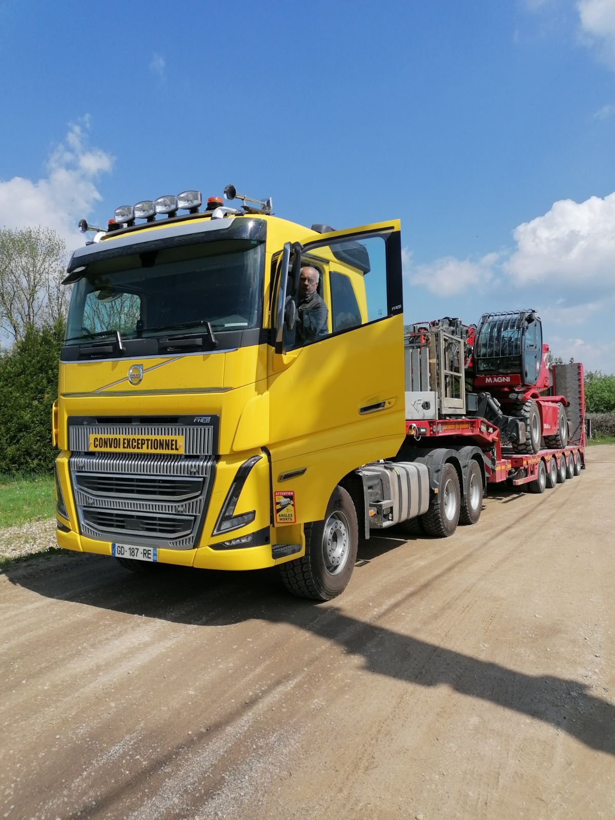 Camion jaune en train de transporter un chariot Magni