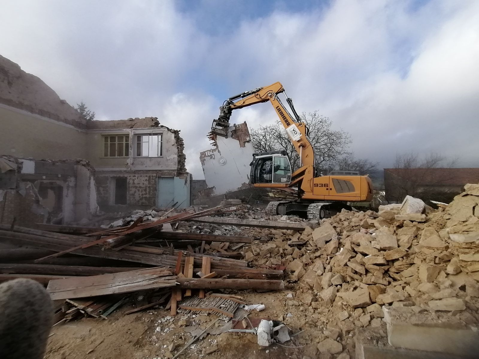 Tractopelle Liebherr sur zone d'intervention en train de détruire une ancienne maison