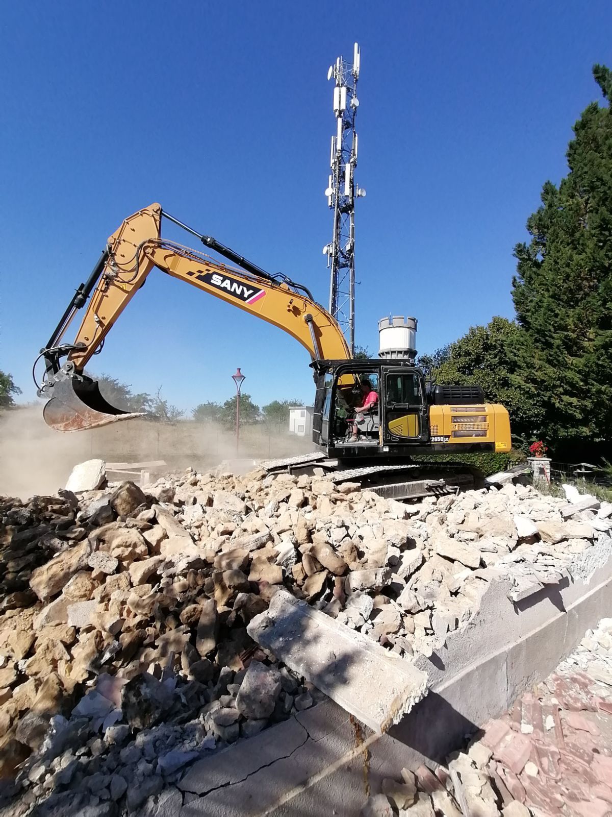 Pelleteuse de destruction avec godet sur un tas de décombre en train d'intervenir