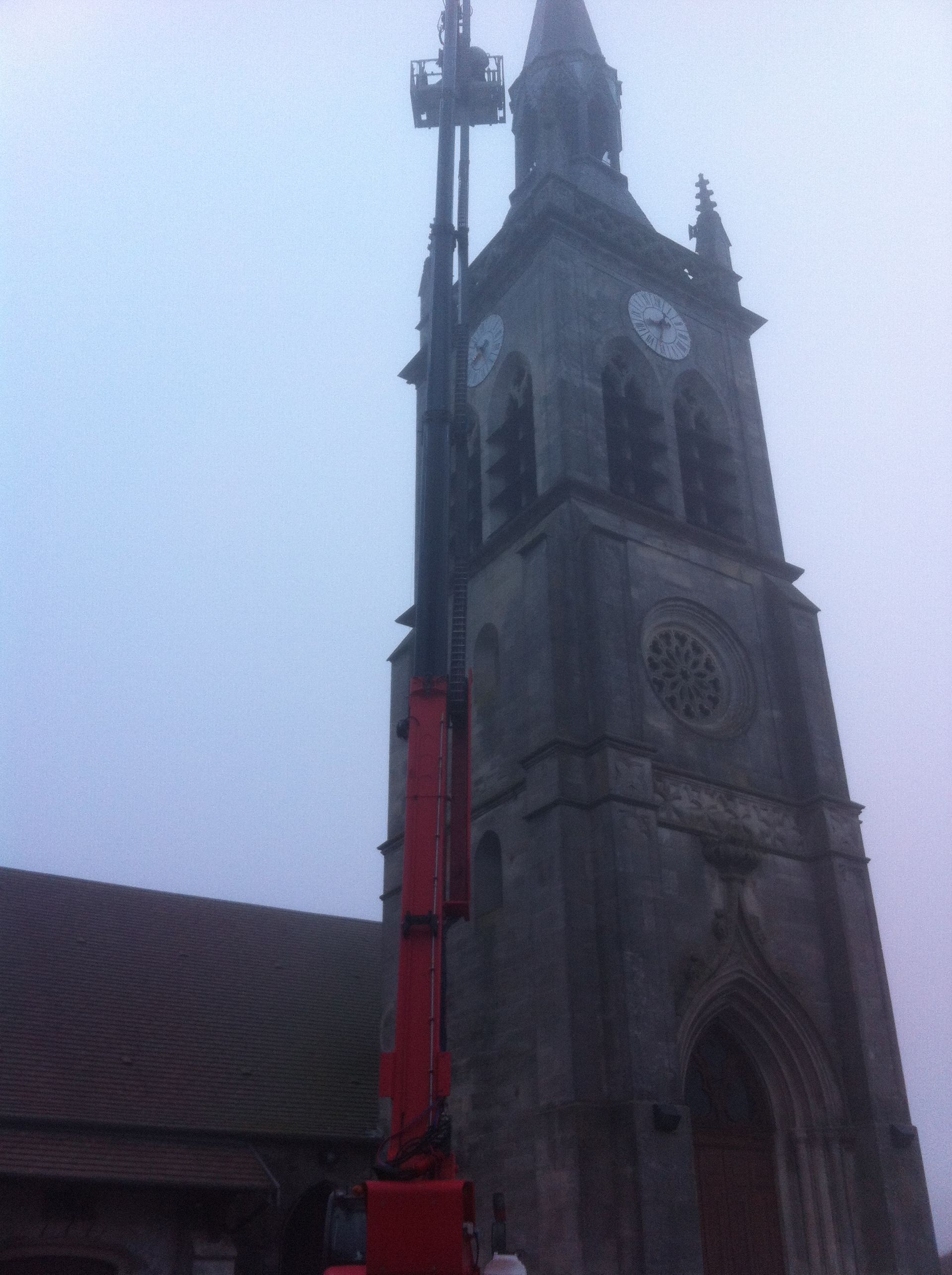 Grue rouge télescopique en intervention sur le clocher d'une église