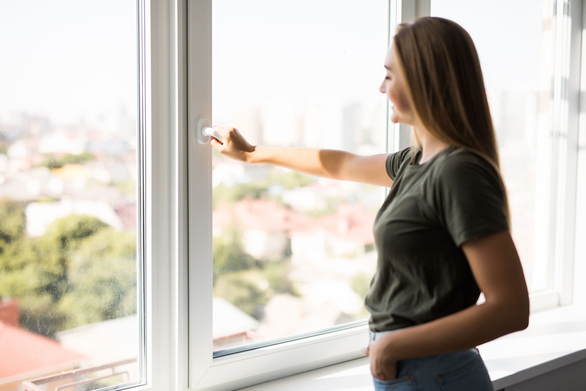 Une personne se tient près d'une fenêtre, la lumière du soleil inondant la pièce.