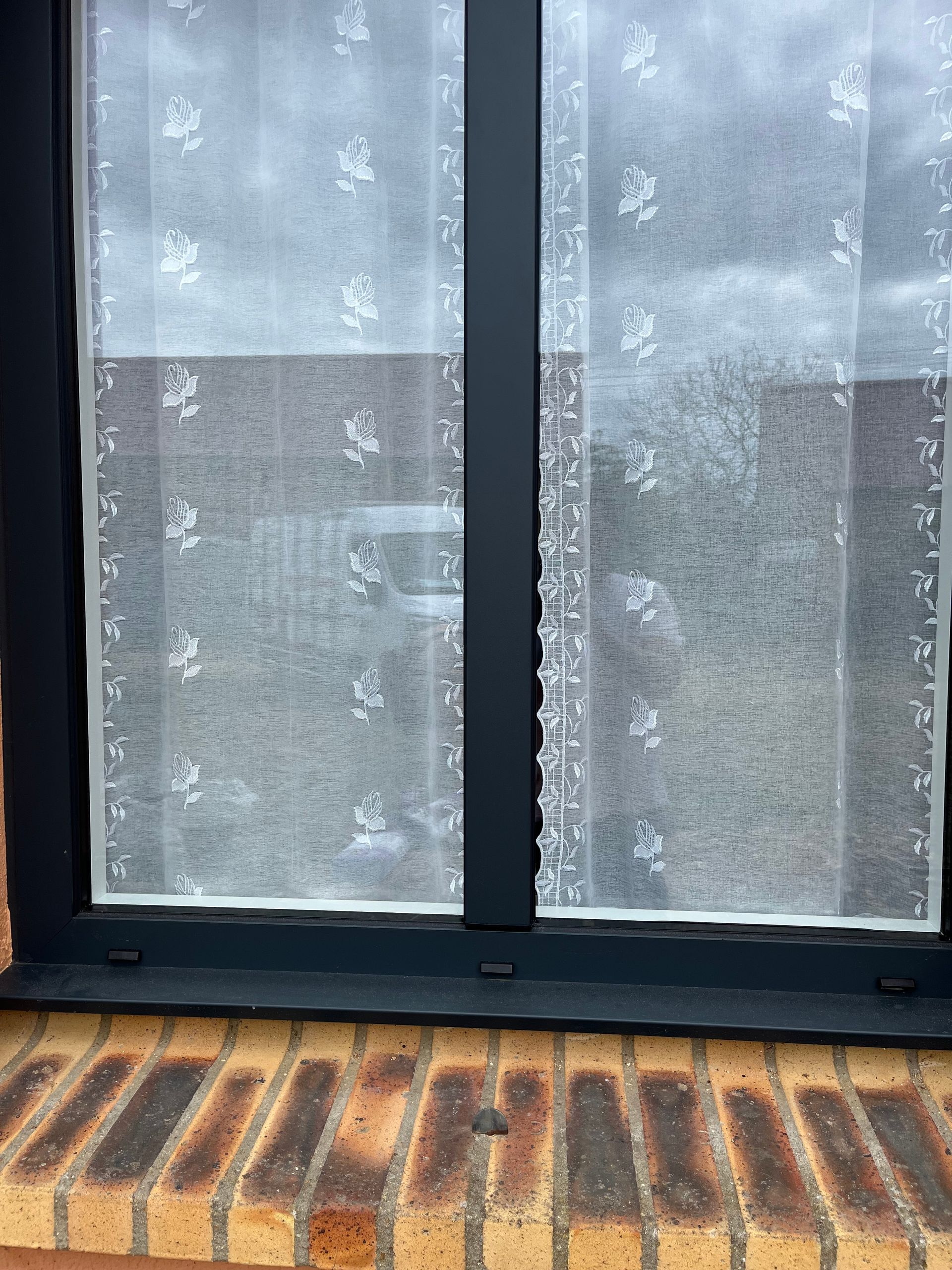 Fenêtre dépolie à cadre noir au-dessus d'un appui de fenêtre en briques à motifs.