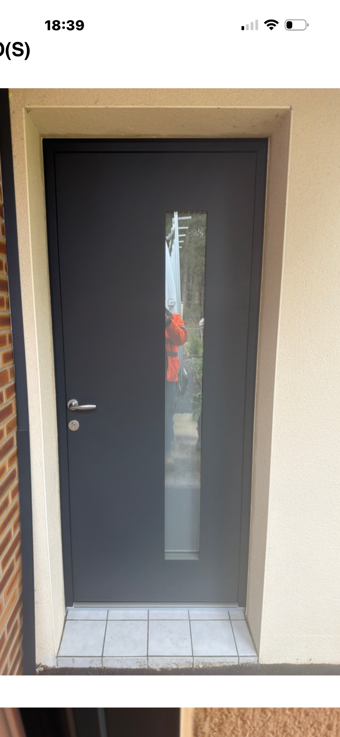 Porte gris foncé avec une étroite fenêtre verticale.