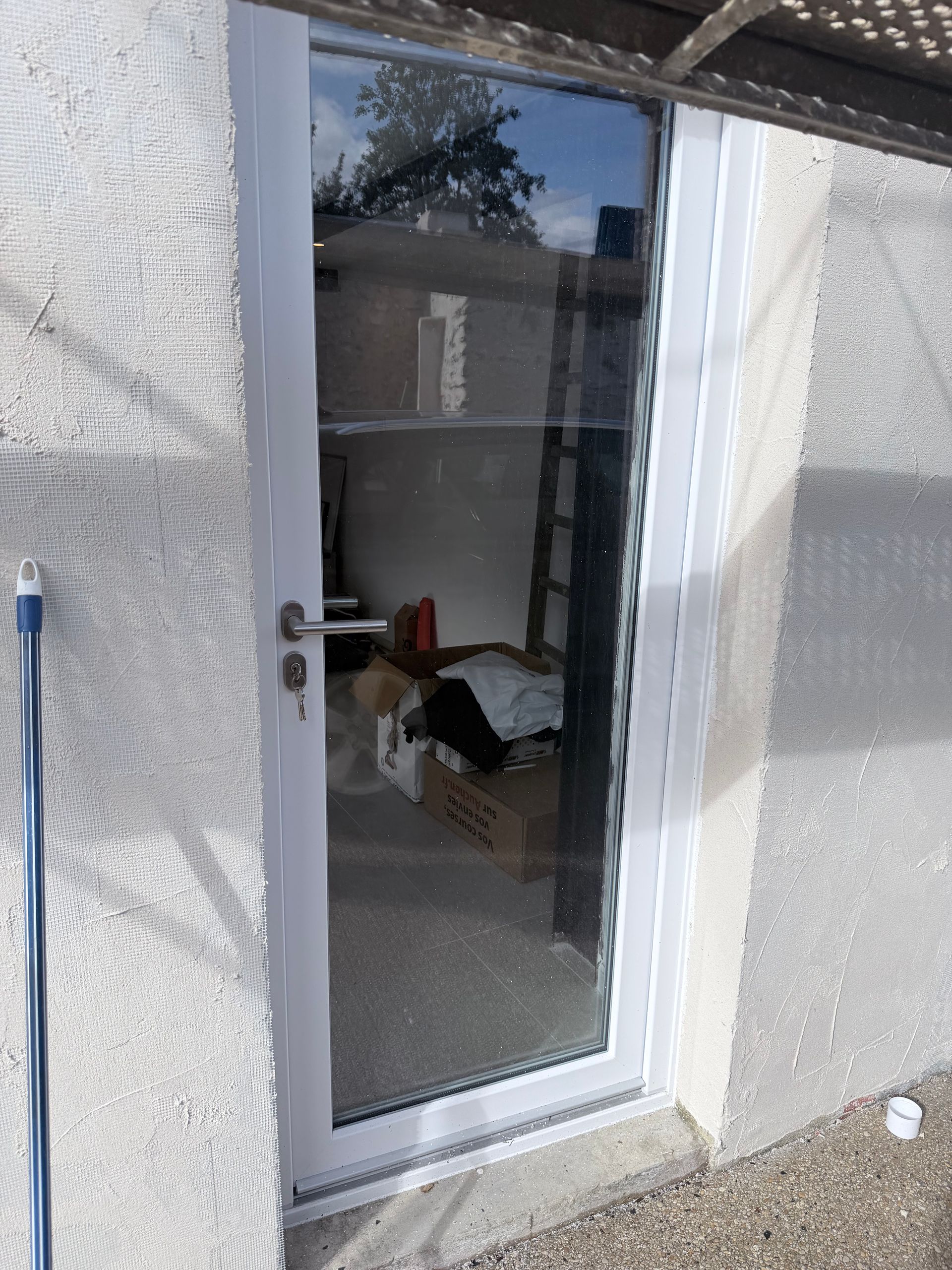 Porte-fenêtre vitrée à cadre blanc encastrée dans un mur.