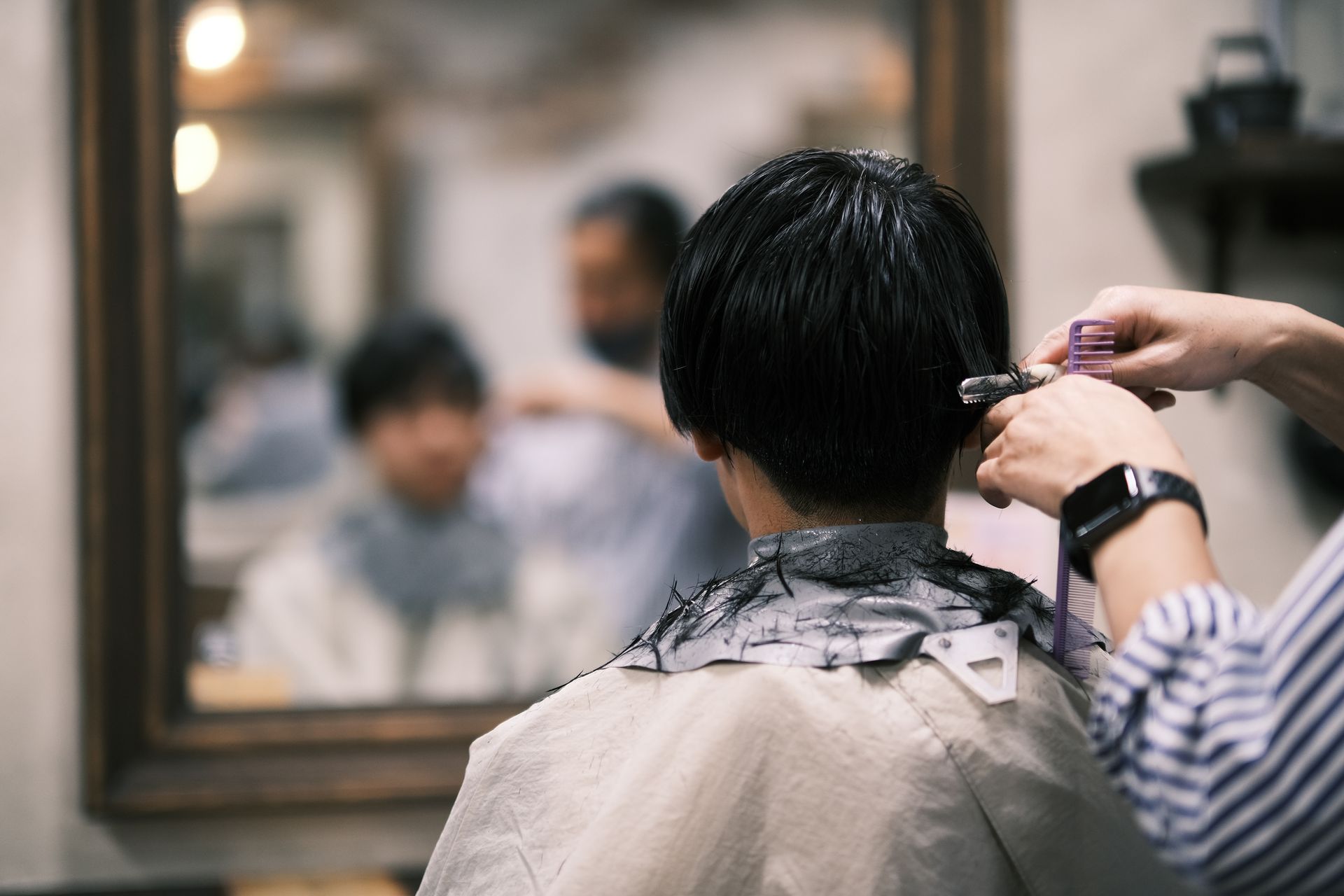 Person beim Haareschneiden; Friseur mit Haarschneidemaschine.