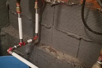 Un montón de tuberías están conectadas a una pared en un baño.