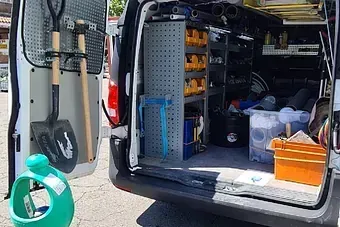 La parte trasera de una camioneta llena de herramientas y una regadera.