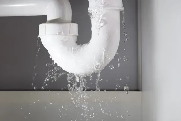 Una tubería del fregadero tiene una fuga de agua y sale agua de ella.