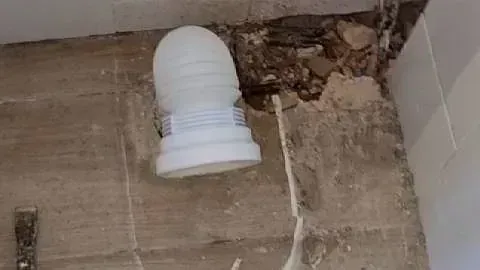 Un cepillo de baño está en el suelo al lado de una tubería.