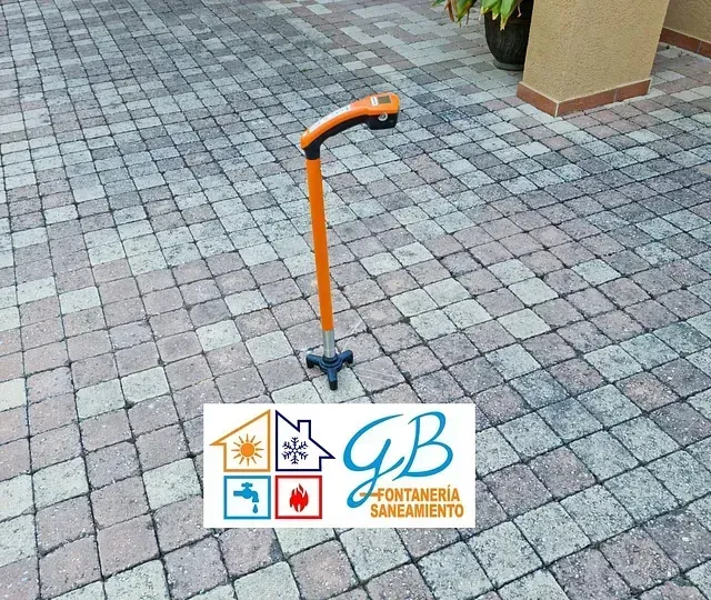 Un bastón está sobre un pavimento de ladrillos junto a un logotipo de GB.