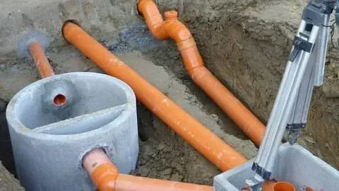 Un montón de tubos están tirados en el suelo junto a un anillo de hormigón.