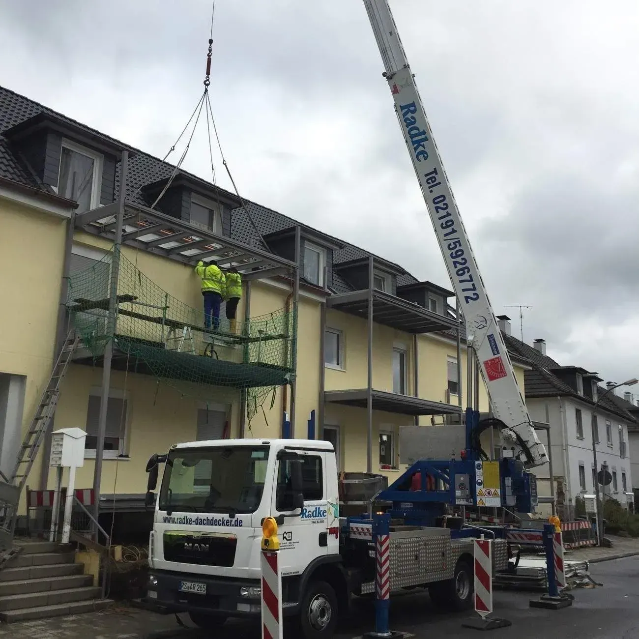 Kran der Firma Dachdeckermeister Radke vor einem Wohnhaus