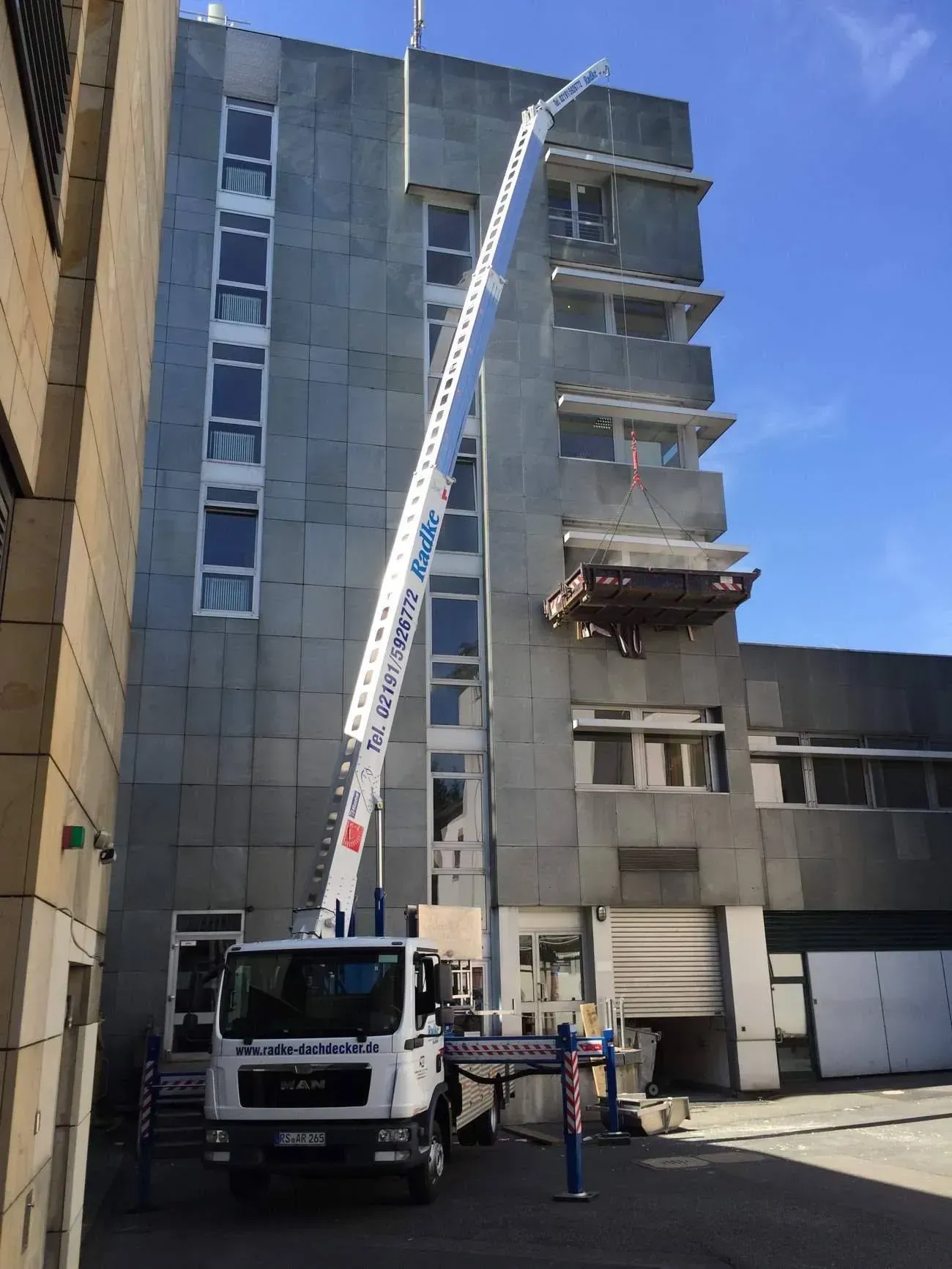 Kran der Firma Dachdeckermeister Radke mit Hebeplattform an einem Hochhaus
