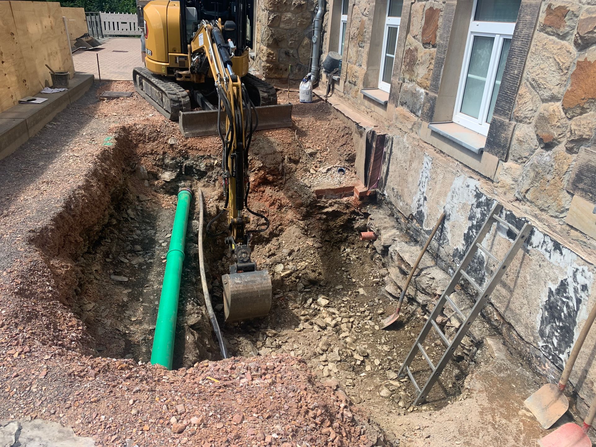 Graben mit vergrabenem Rohr, schwere Maschinen heben und positionieren das Rohr, Baustelle, im Freien.