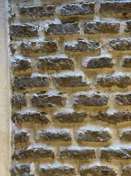 Primer plano de una pared de ladrillo color canela desgastada con líneas de mortero blanco.