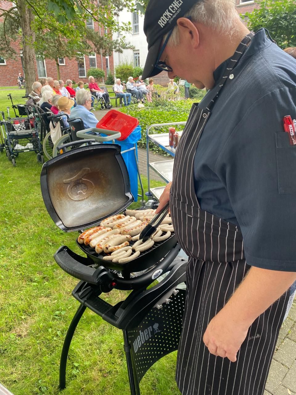 Magdalenen-Heim Aldekerk - Mann grillt Würstchen auf einem Kohlegrill