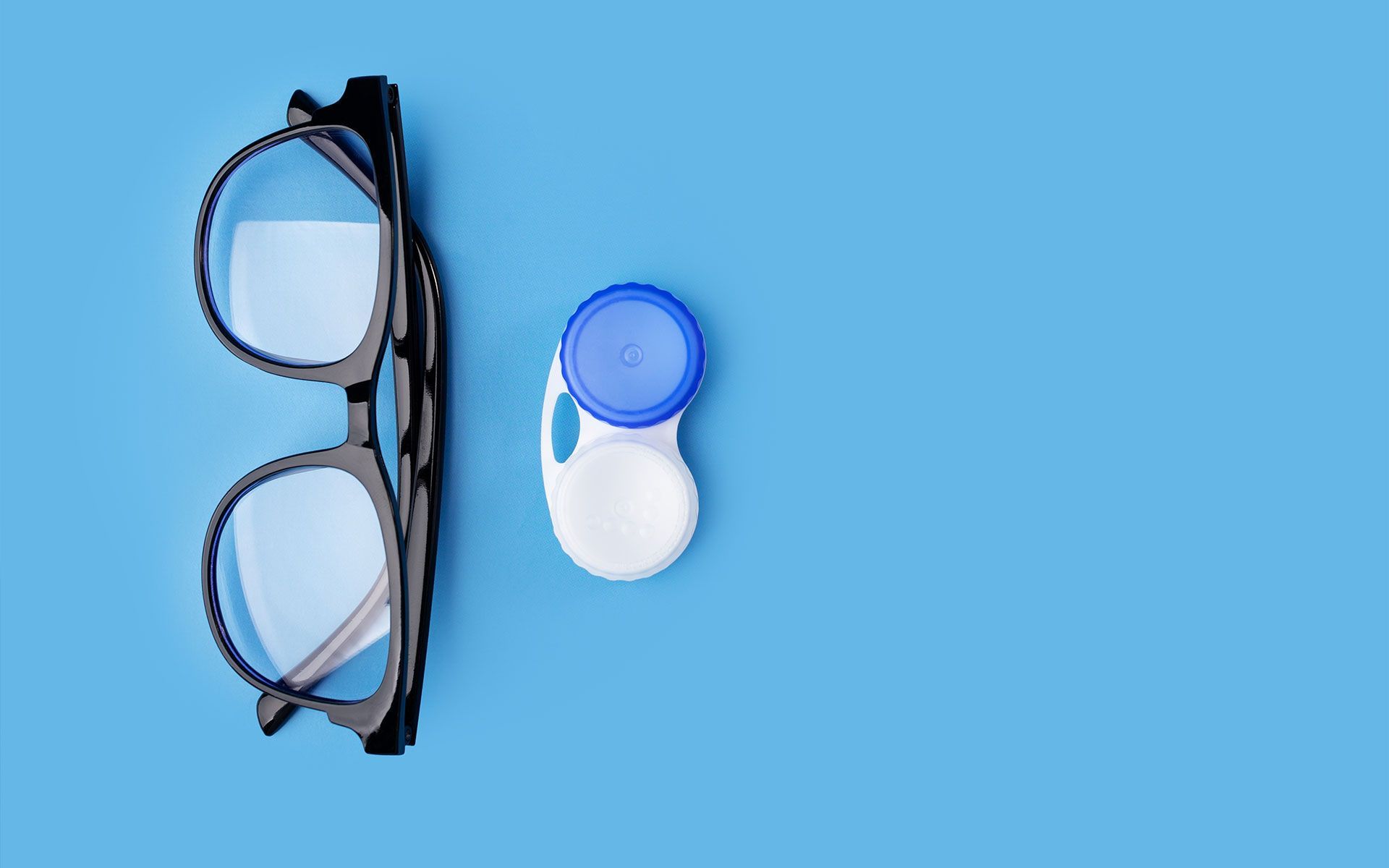 Brille und Kontaktlinsenetui auf blauem Hintergrund