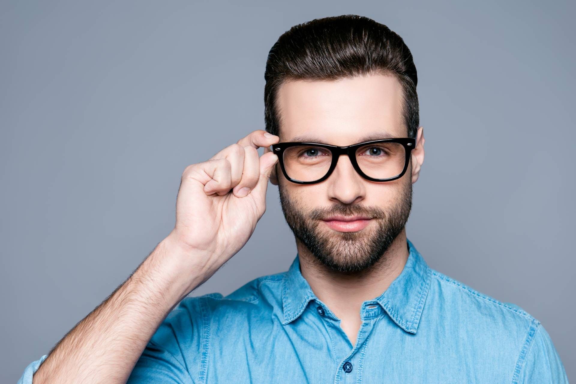ein Mann mit Bart hält seine Brille