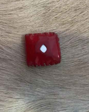 Cuadrado rojo con diamante blanco sobre una superficie peluda.