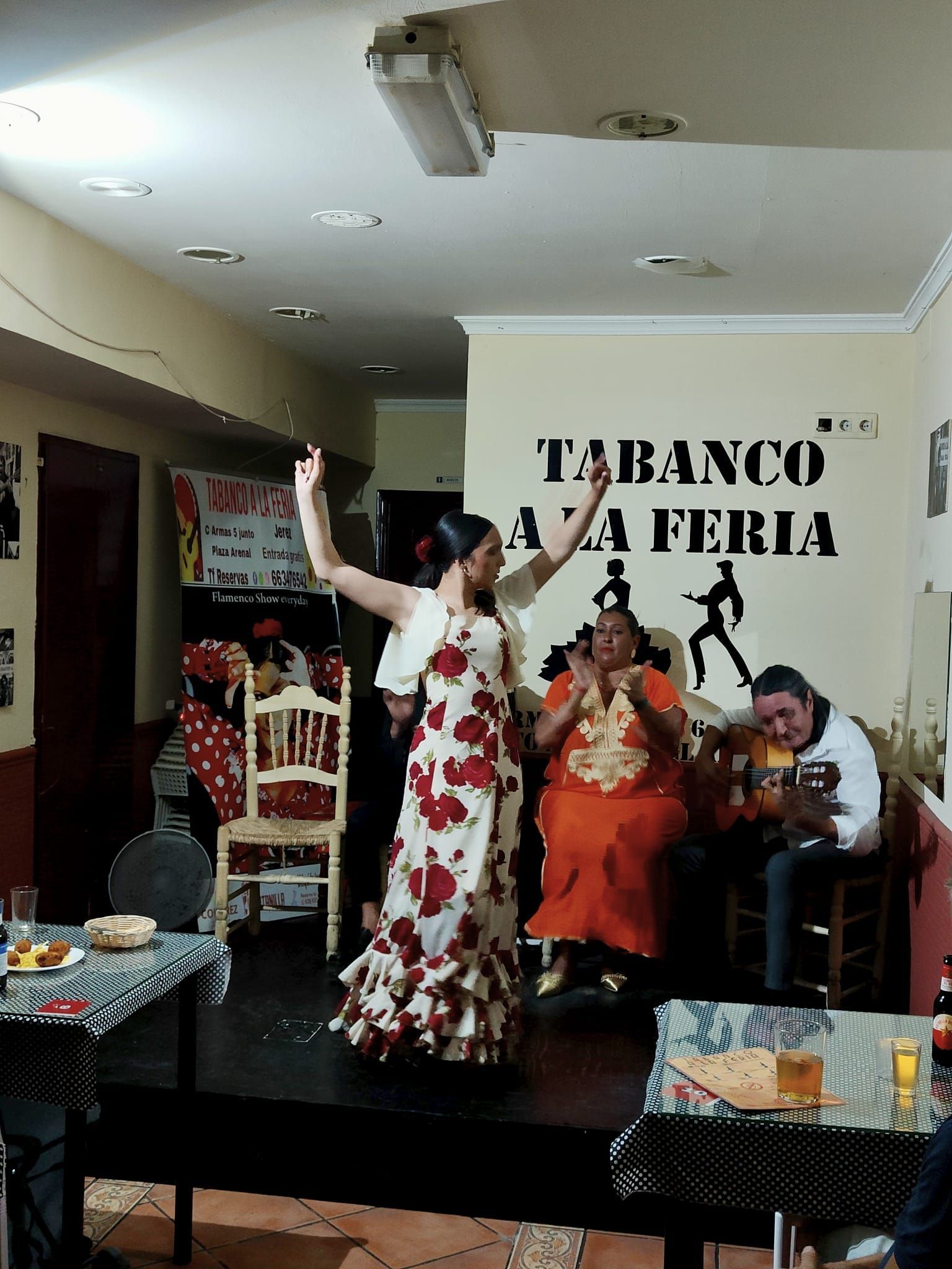 Una mujer está bailando frente a una pared que dice tabaco a la feria