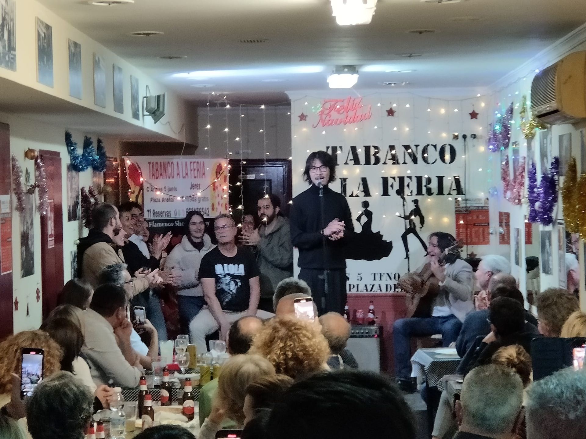 Un grupo de personas se reúnen en una habitación con un cartel que dice tabanco la feria