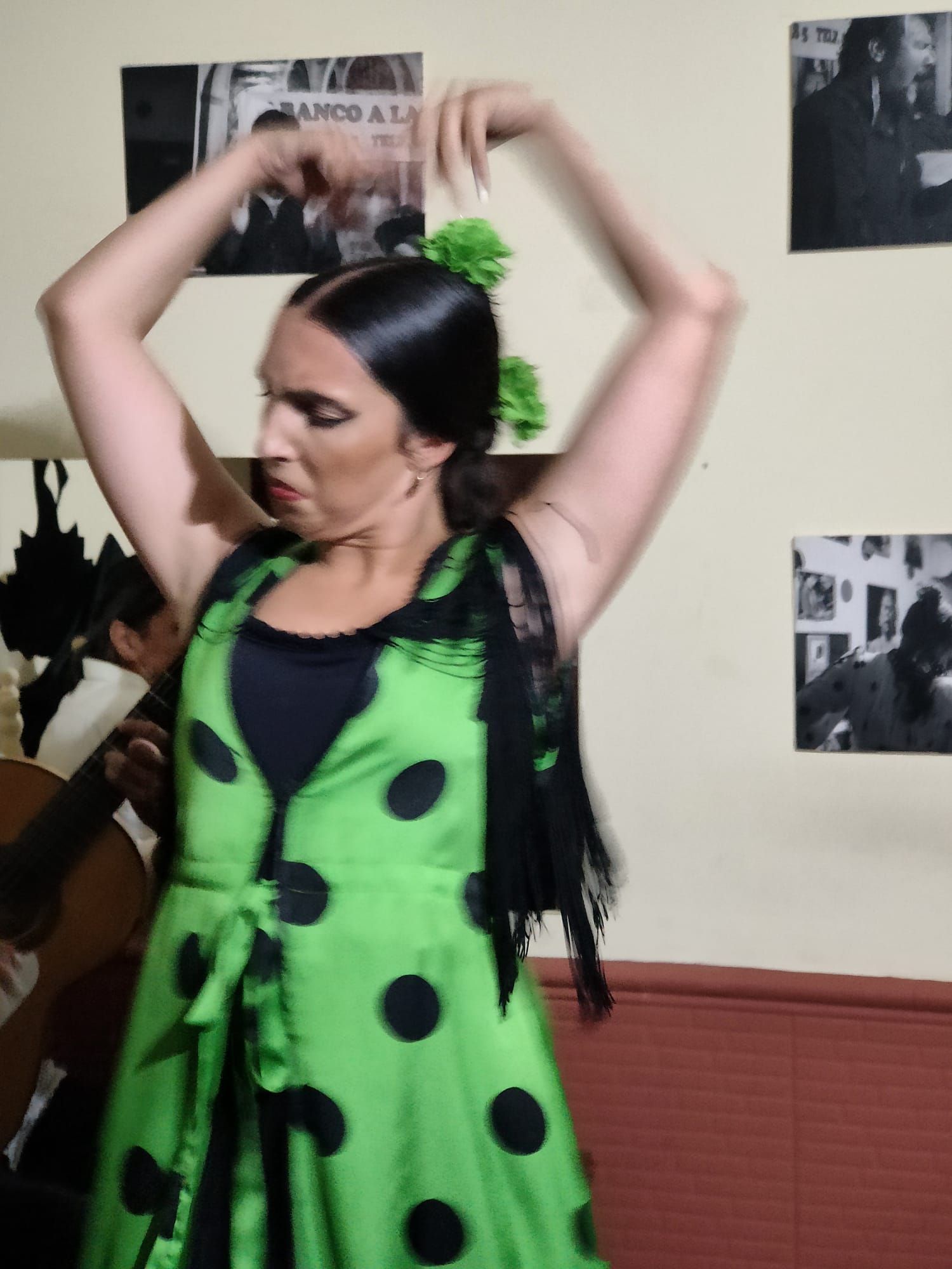 Una mujer con un vestido de lunares verdes y negros está bailando.
