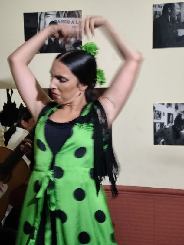 Una mujer con un vestido de lunares verdes y negros está bailando.