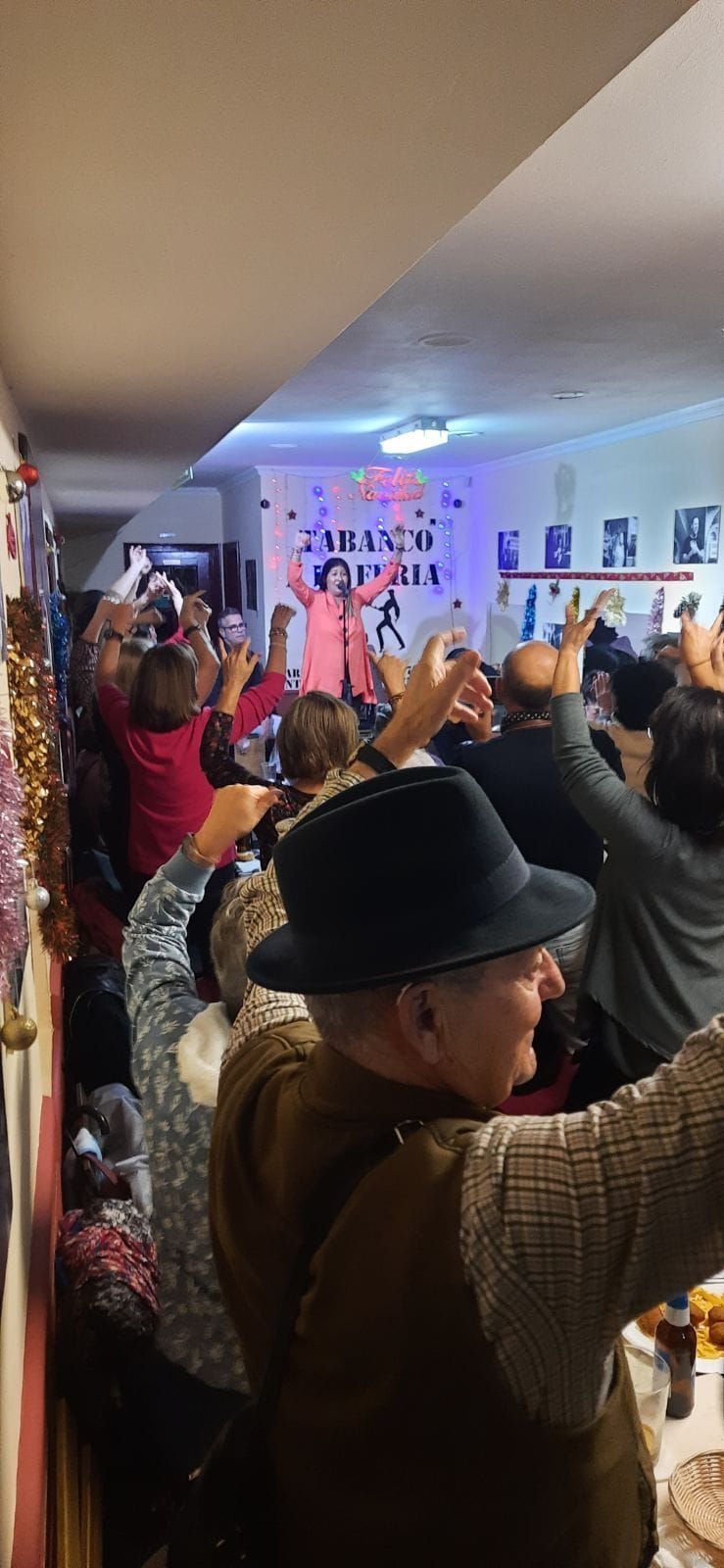 Un grupo de personas está de pie en una habitación con los brazos en el aire.