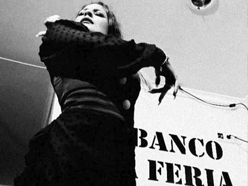 Una mujer está bailando frente a un cartel que dice banco feria