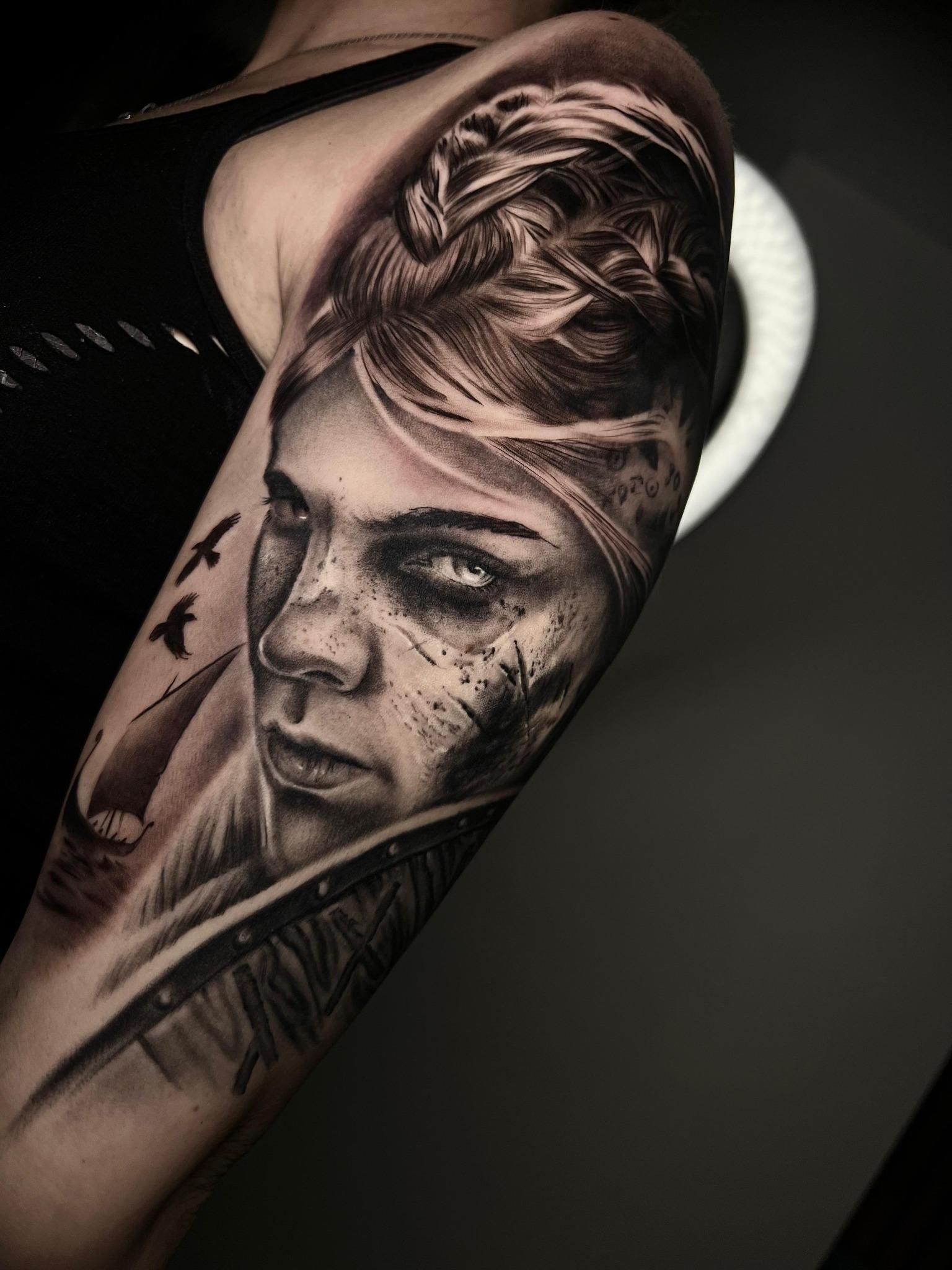 Una mujer tiene un tatuaje de la cara de una mujer en su brazo.