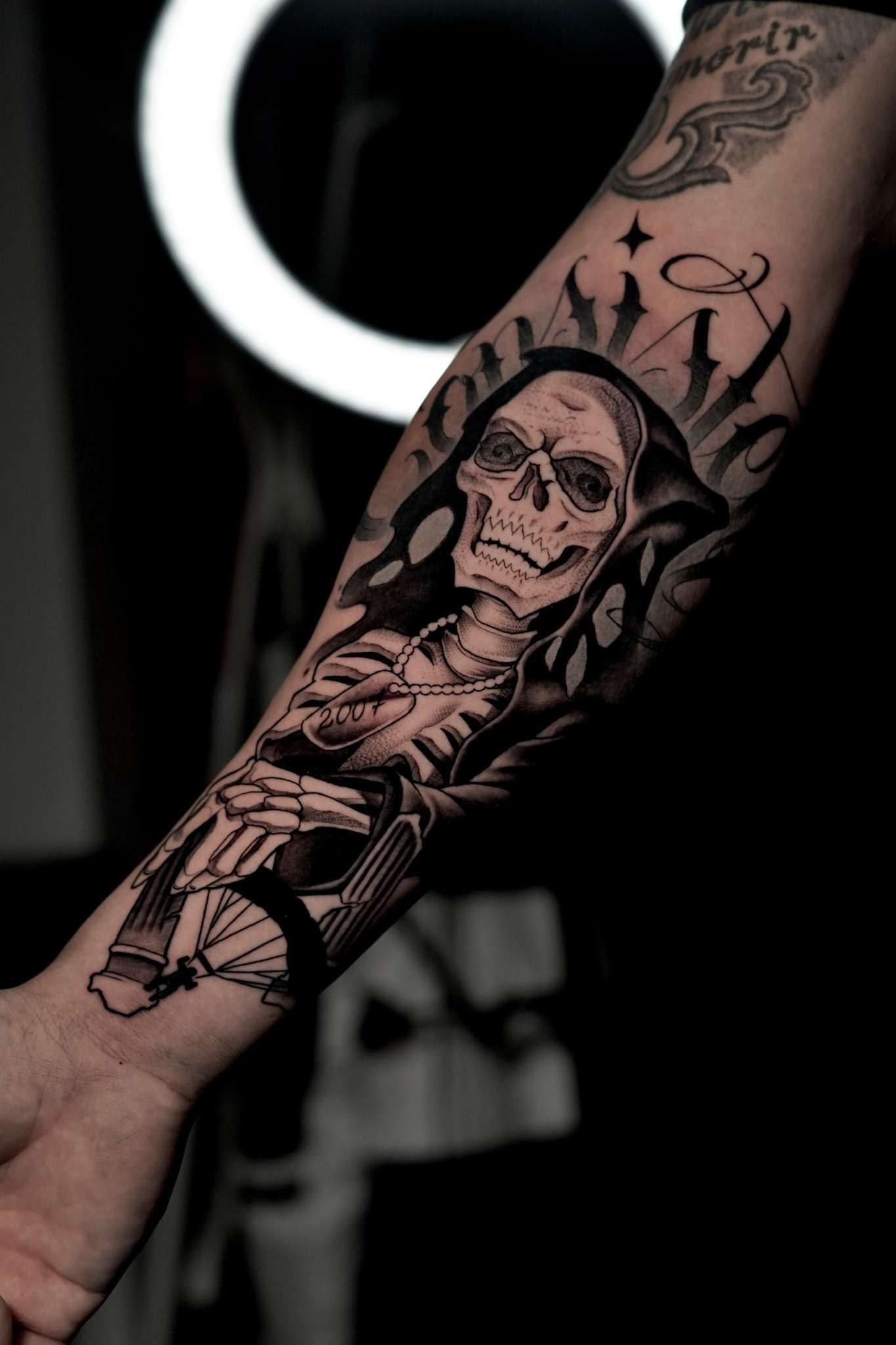 Un hombre tiene un tatuaje de la parca en su antebrazo.