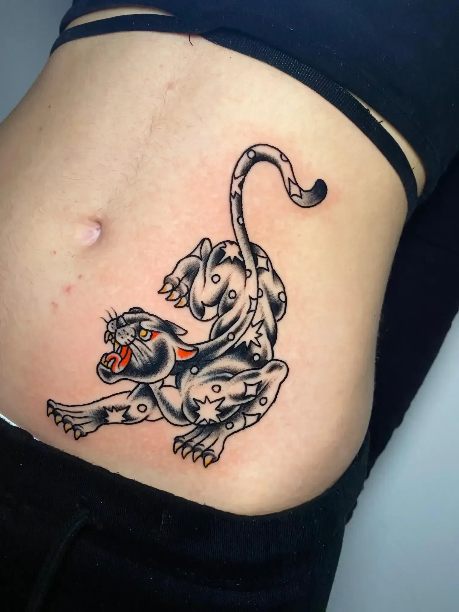 Una mujer tiene un tatuaje de una pantera en el estómago.