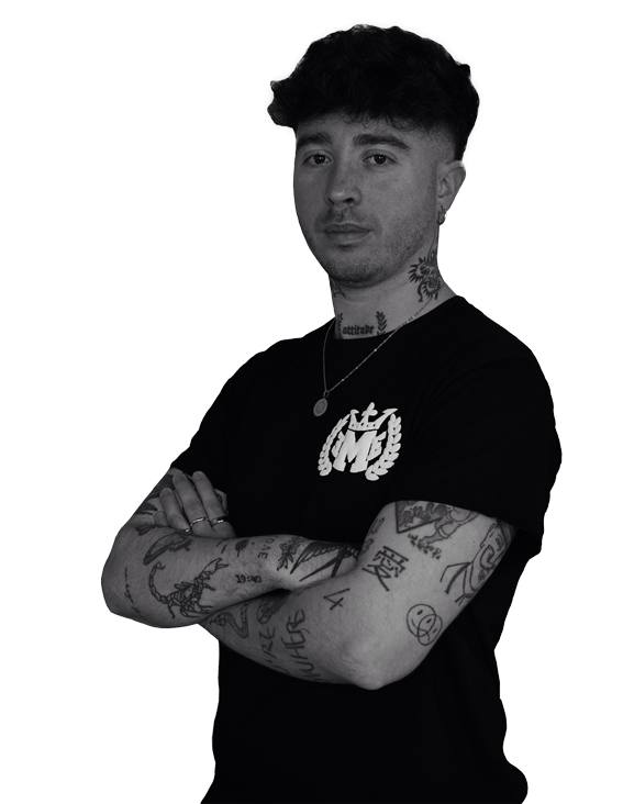 Un hombre con muchos tatuajes en sus brazos está de pie con los brazos cruzados.